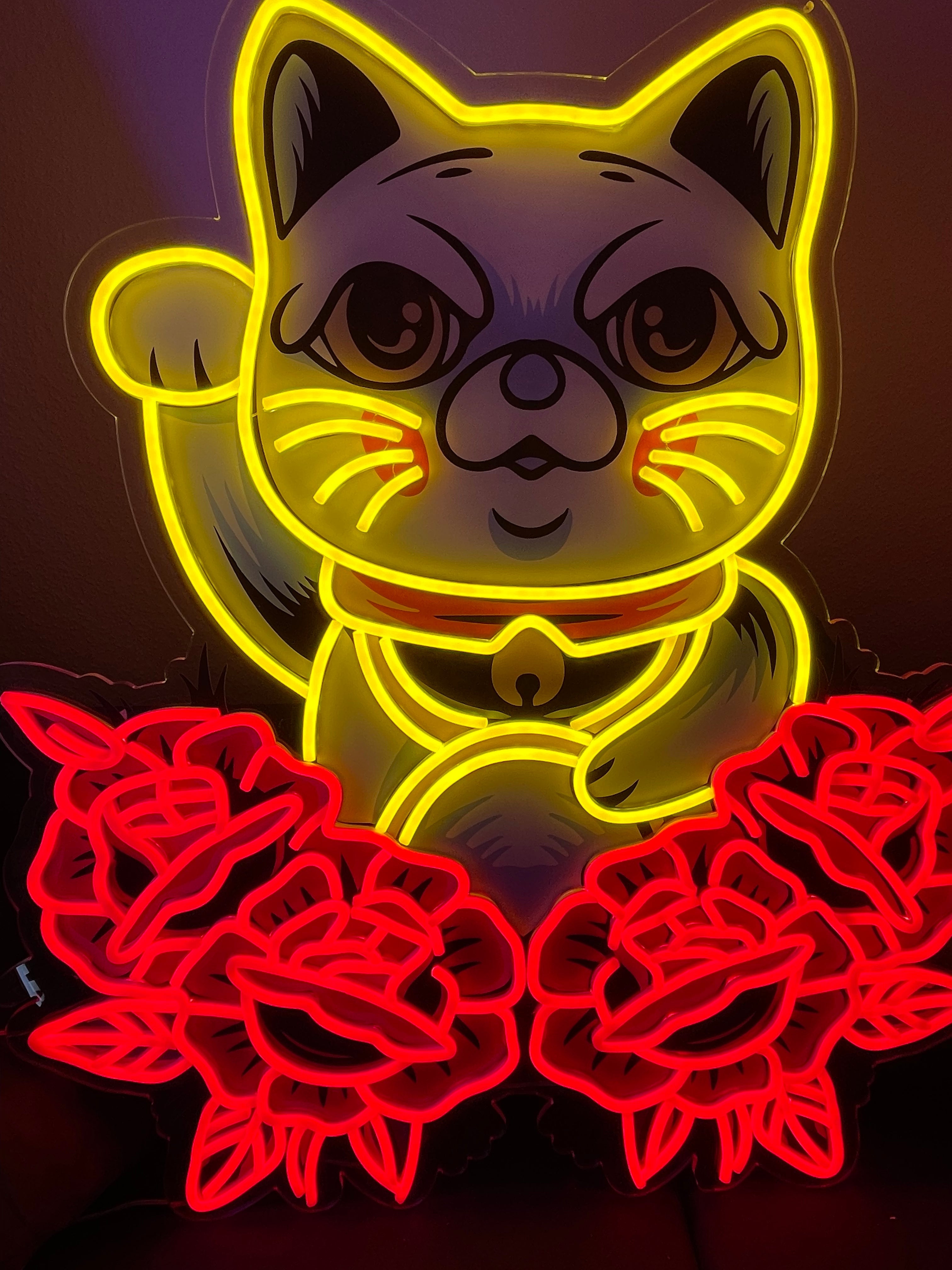 A neon sign of lucky cat in yellow with red roses